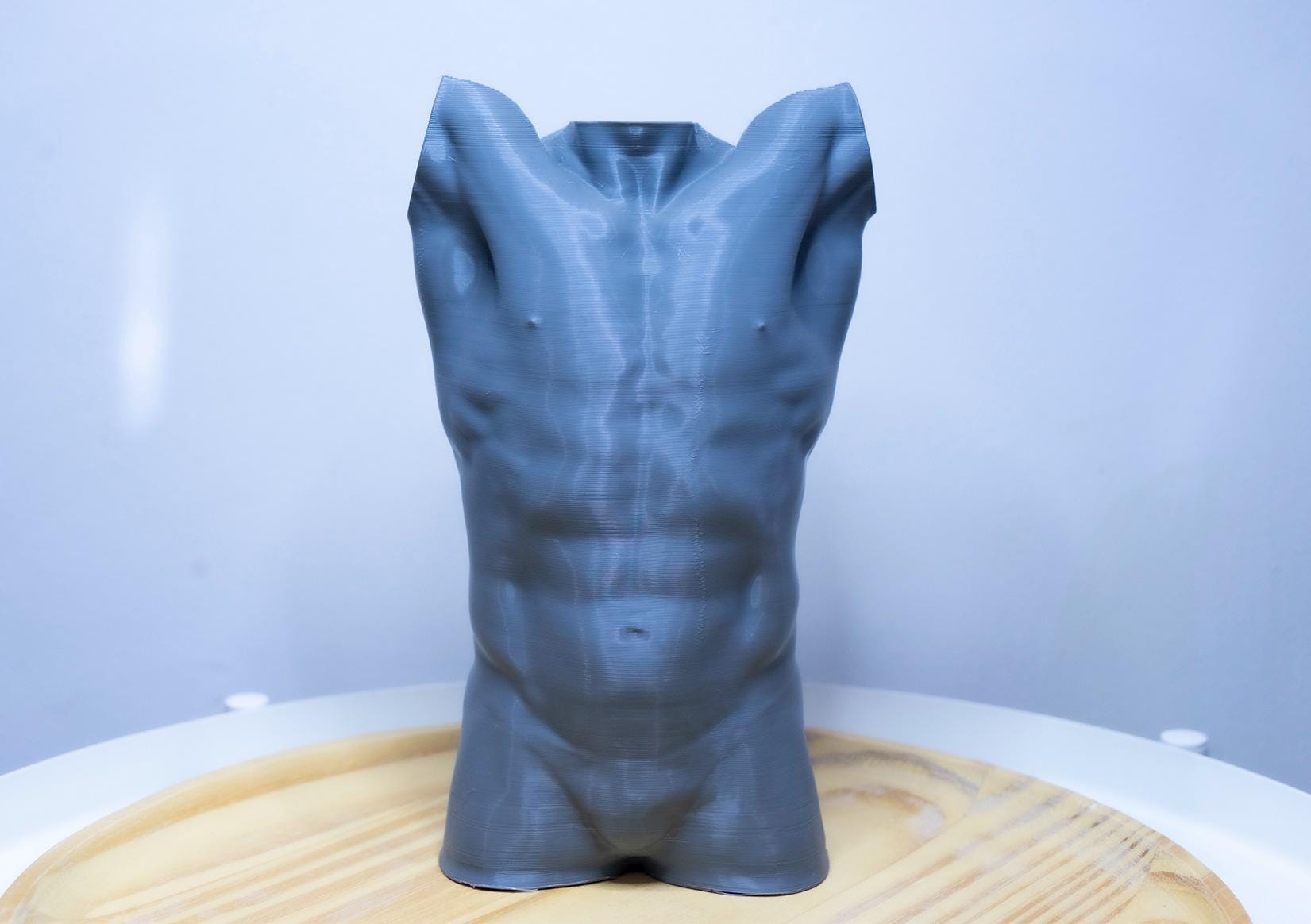 Male torso anatomy sculpture with raised arm for artists. Figure drawing reference model for studying ribcage stretch and muscular structure. grey sculpture
