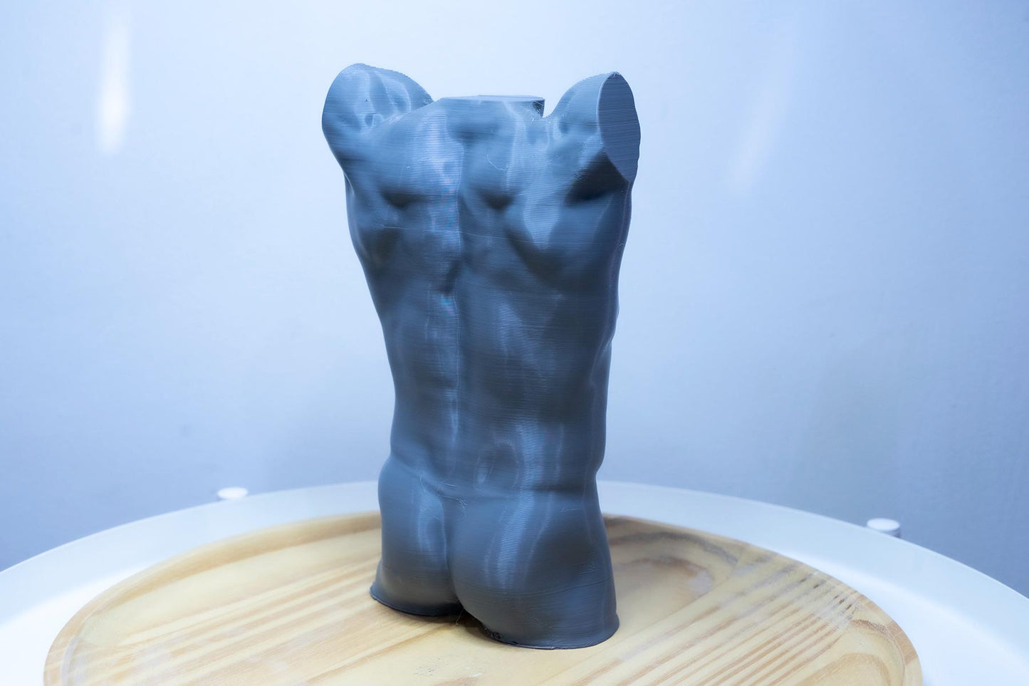 Male torso anatomy sculpture with raised arm for artists. Figure drawing reference model for studying ribcage stretch and muscular structure. grey sculpture